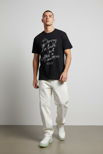 Black t-shirt with white text 'Sorry I'm late but coffee matters' on a white background