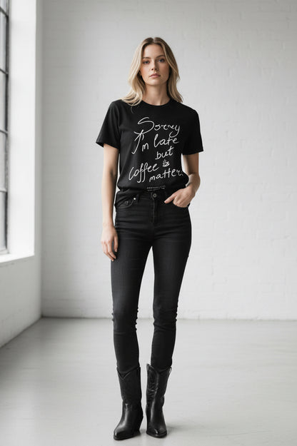 Black t-shirt with white text 'Sorry I'm late but coffee matters' on a white background