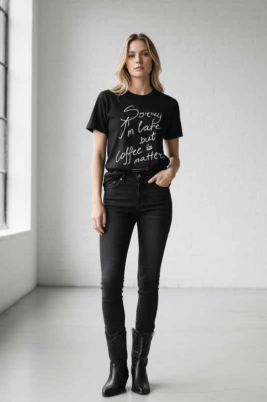Black t-shirt with white text 'Sorry I'm late but coffee matters' on a white background